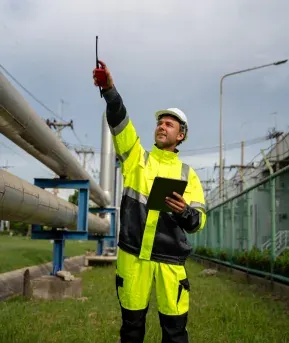 Engineer on radio alongside pipeline infrastructure